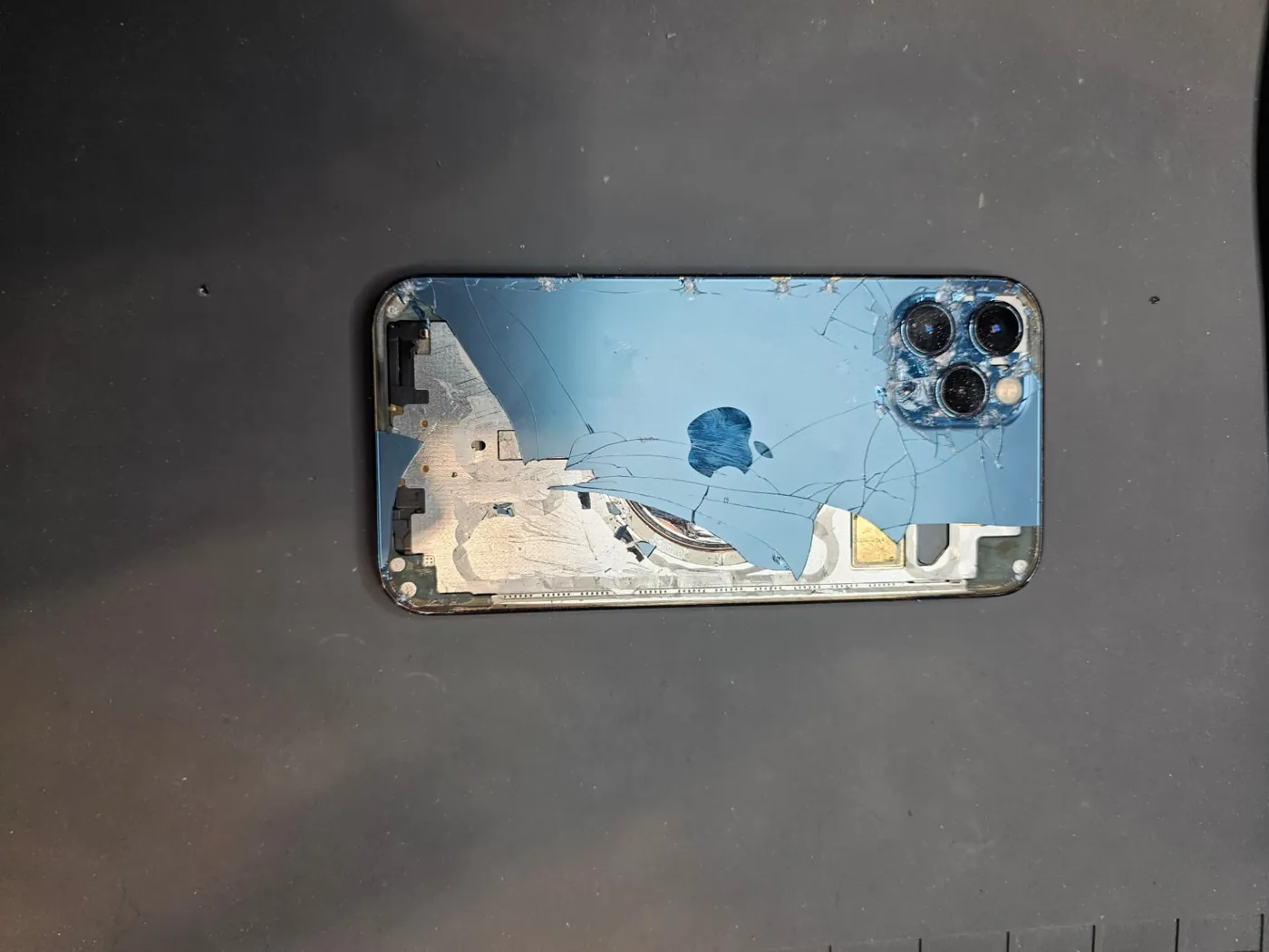 Shattered blue iPhone 12 Pro back glass on a repair mat before replacement in Adelaide